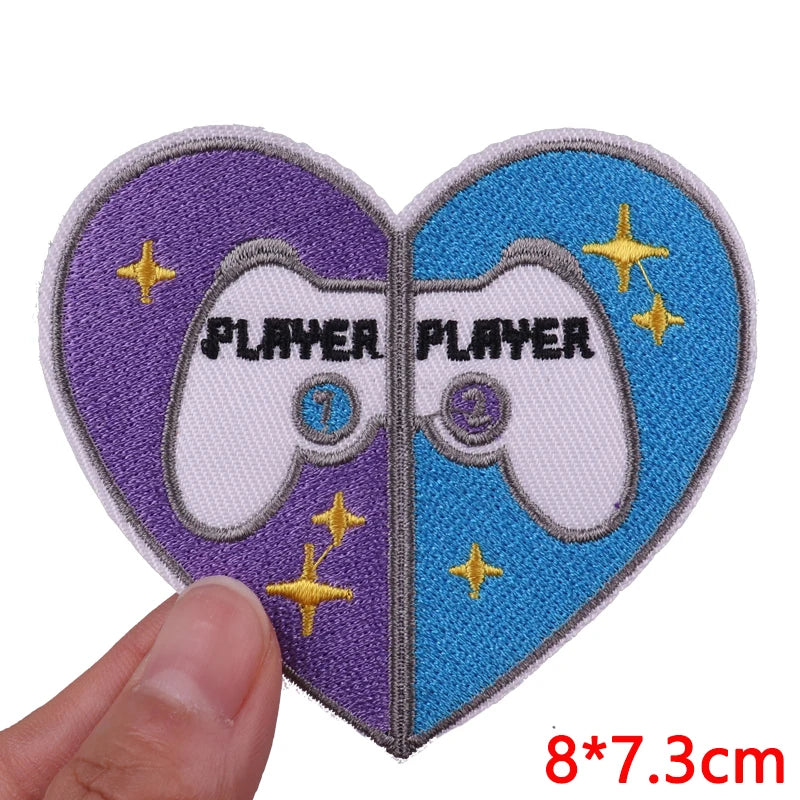A pair of heart-shaped embroidered iron-on patches featuring a white controller design with the word PLAYER on each half.