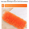 An orange extendable microfiber duster is shown cleaning a white surface.
