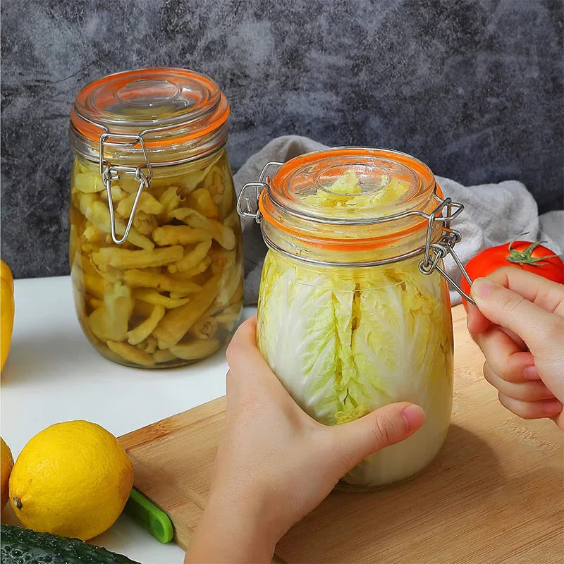 Hands are squeezing a glass mason jar filled with sliced cucumbers and herbs on a wooden cutting board.