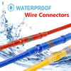 A close-up of various waterproof wire connectors in red, blue, and yellow colors being splashed by water.