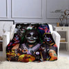 A dark graphic print of the Kiss band members on a flannel throw blanket displayed on a white sofa.