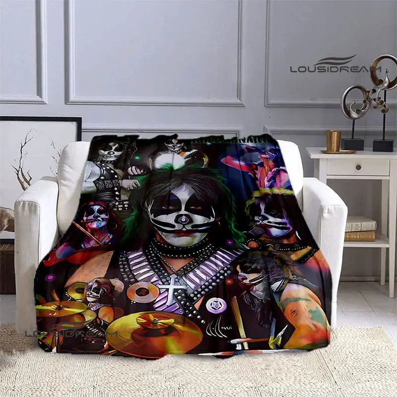 A dark graphic print of the Kiss band members on a flannel throw blanket displayed on a white sofa.