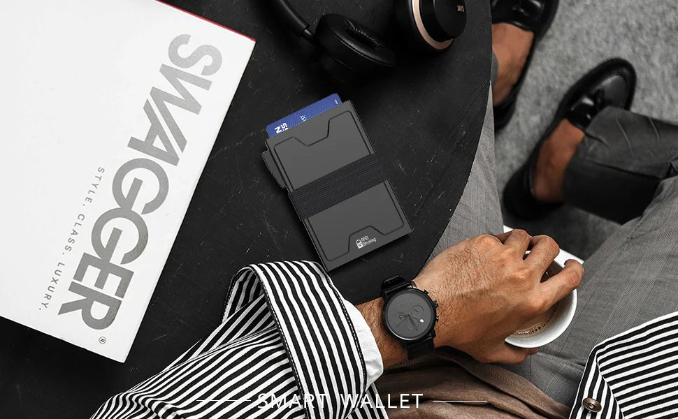 Eine Hand hält eine schwarze Smart-Wallet neben einer Zeitschrift, die einen schlanken Metall-Kartenhalter mit RFID-Blockieru