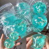 A hand holds a clear blue ocean squishy stress ball filled with sea life for sensory play.