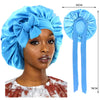 A woman is wearing a bright blue silky satin sleep cap with a wide band, shown alongside the product dimensions.