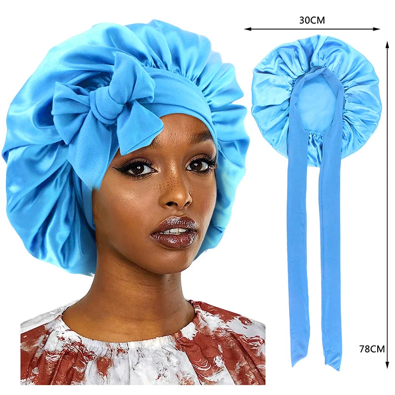 A woman is wearing a bright blue silky satin sleep cap with a wide band, shown alongside the product dimensions.