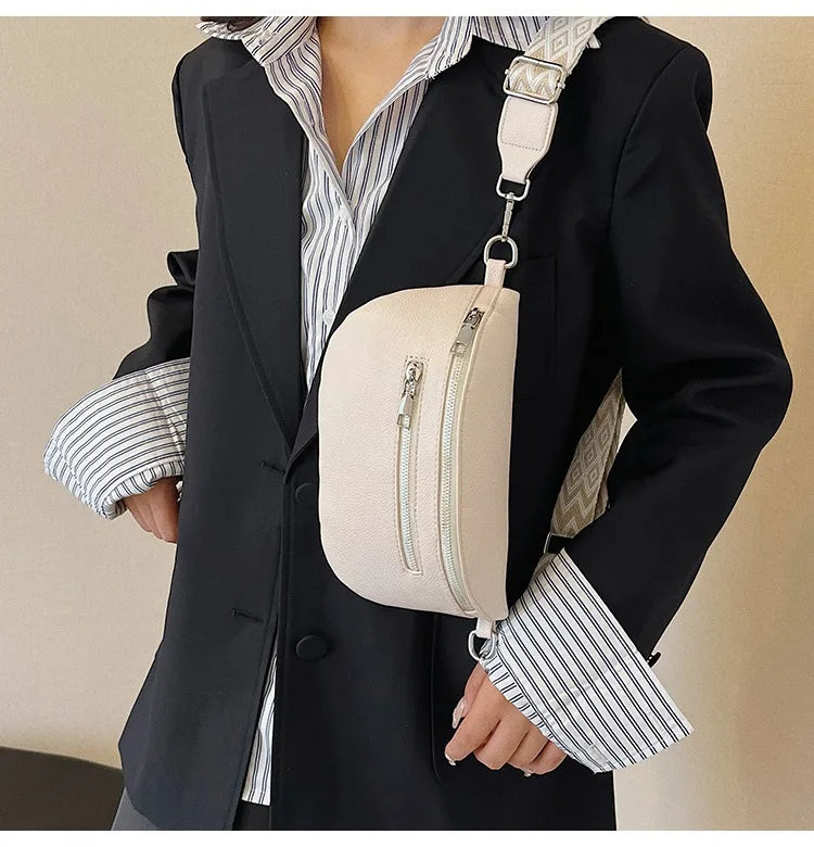 A woman wearing a black blazer and striped shirt holds a cream-colored multi-pocket PU leather waist bag with an adjustable s