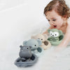 A baby is playing with silicone animal finger puppet bath toys in a bathtub filled with water.