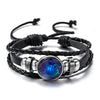 Black leather wrap bracelet featuring a glowing blue zodiac sign charm.