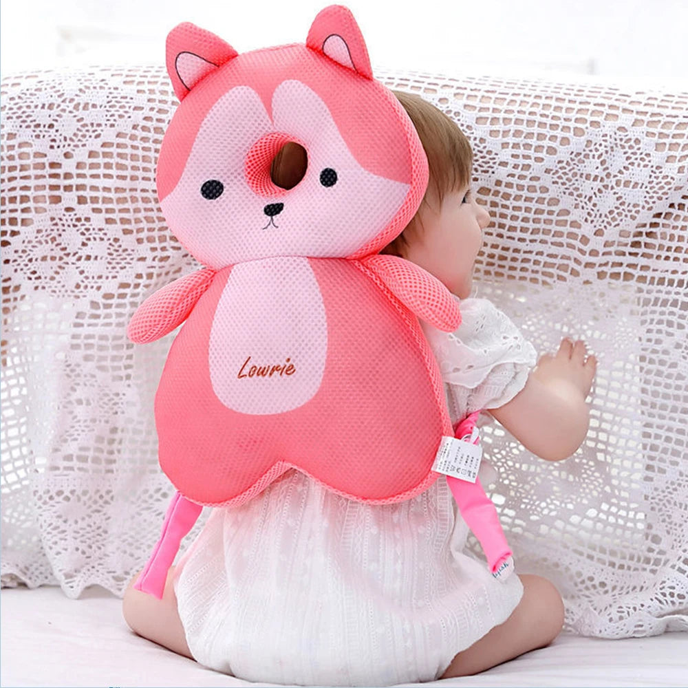 A pink toddler head protector shaped like a fox is worn by a baby girl.