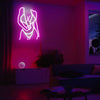 A pink neon silhouette wall sign depicting a figure in a dynamic pose illuminates a modern living room.