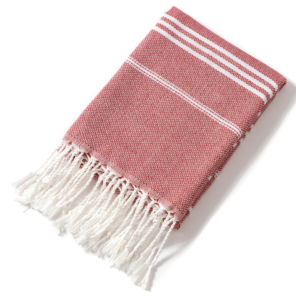 A folded pink and white striped cotton beach towel with frayed edges.