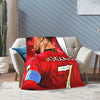 Rote Fußballtrikot-Wolldecke über einem hellgrauen Sofa