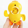 A yellow wind-up bath toy duck is held in a hand, showing its body and orange feet.