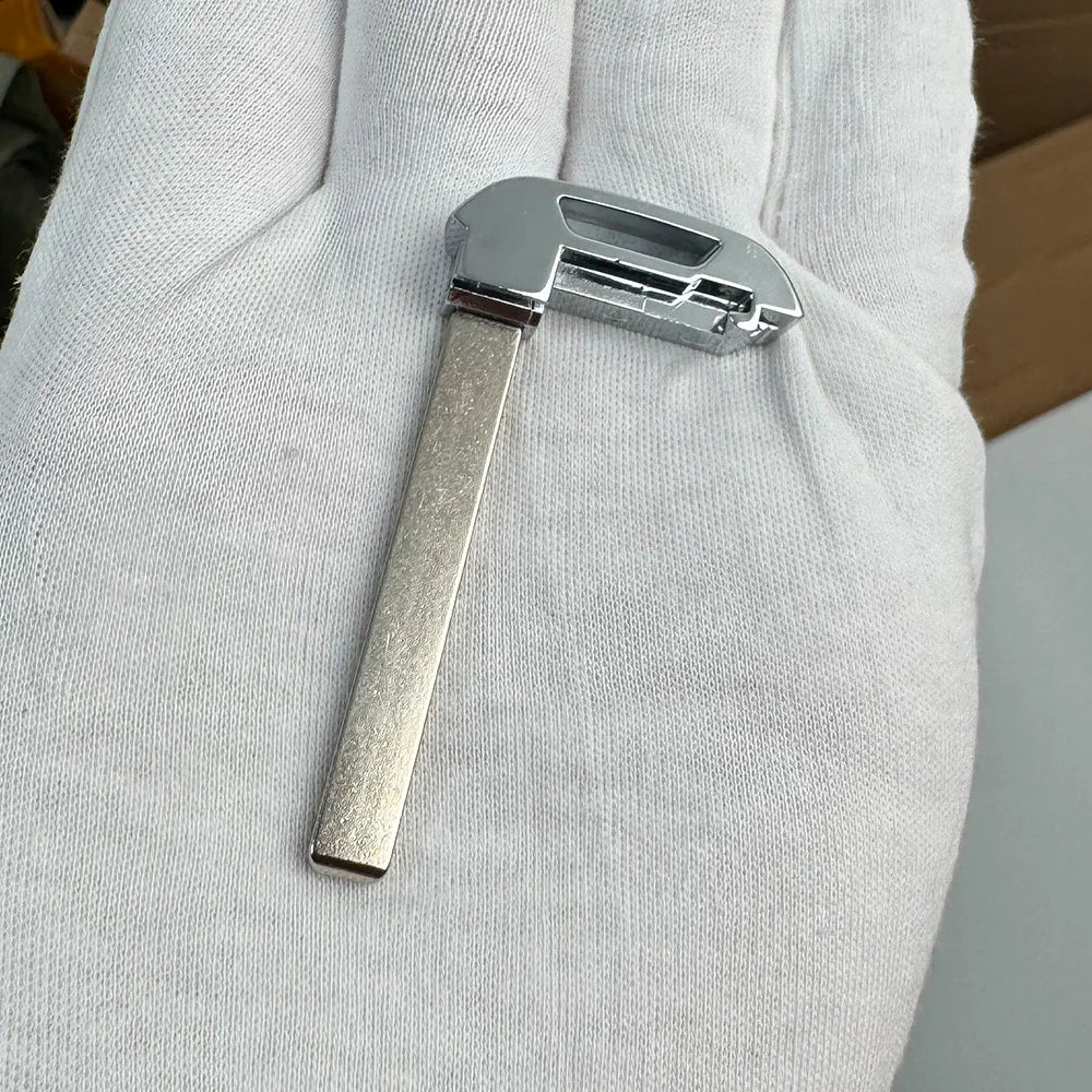 A close-up of a silver replacement remote key for Chevrolet and GMC vehicles held in a person's hand.