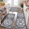 A long rectangular gray and white patterned kitchen rug placed on a wooden floor next to white cabinets.