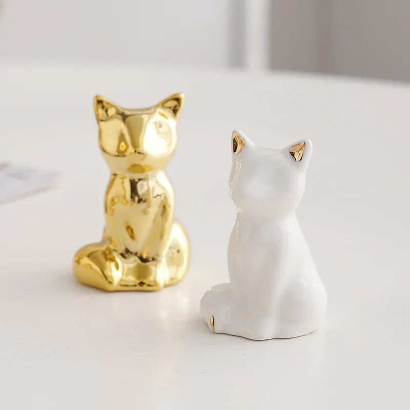 A pair of handcrafted ceramic elephant and rabbit jewelry holders or desk ornaments, one gold and one white.