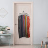 A metal pant hanger with ten clips hanging on a white door, displaying various colored garments.
