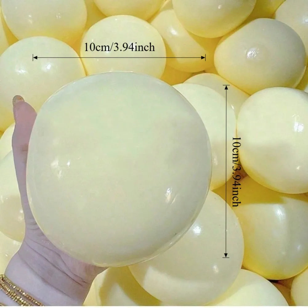 Eine Hand hält einen großen, glatten, blassgelben sensorischen Stressabbau-Squishy-Fidget-Ball mit einem Messindikator.