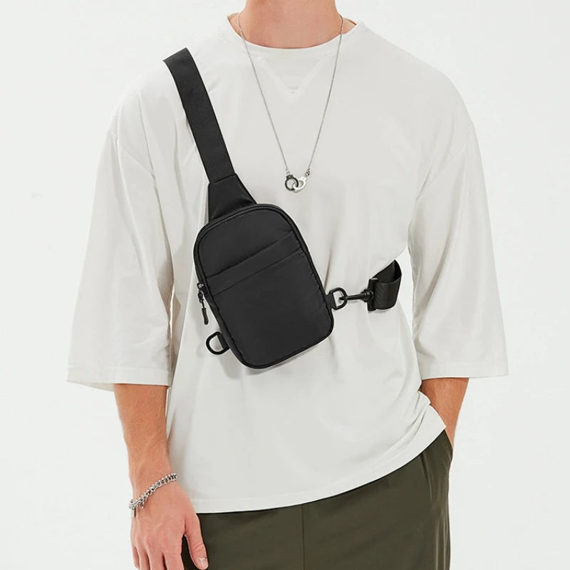 A person wearing a white t-shirt displays a black 2-in-1 convertible waist and crossbody sling bag.