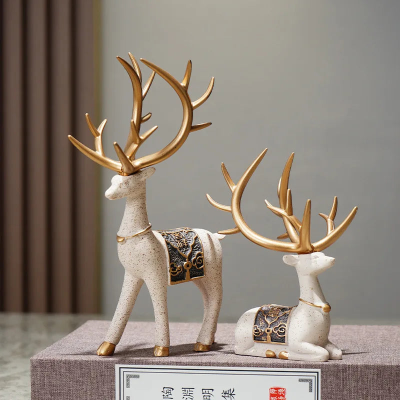 A set of two resin deer figurines, one standing and one seated, with golden antlers and decorative patterns.