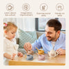 A man and a toddler are playing with a bear silicone pretend play teapot set on a wooden table.
