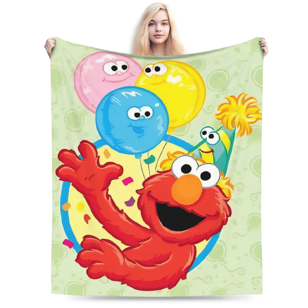 A person is holding a green Sesame Street Friends flannel throw blanket featuring a smiling orange monster character.
