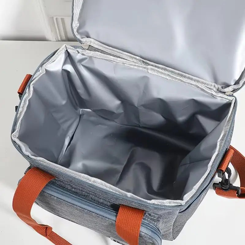 A gray insulated lunch bag with a silver lining is shown open, displaying double-layer compartments and orange straps.