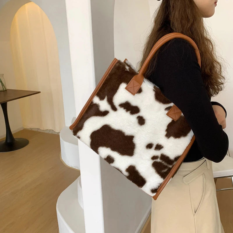 A woman holds a brown faux fur leopard print tote bag in a light indoor setting.