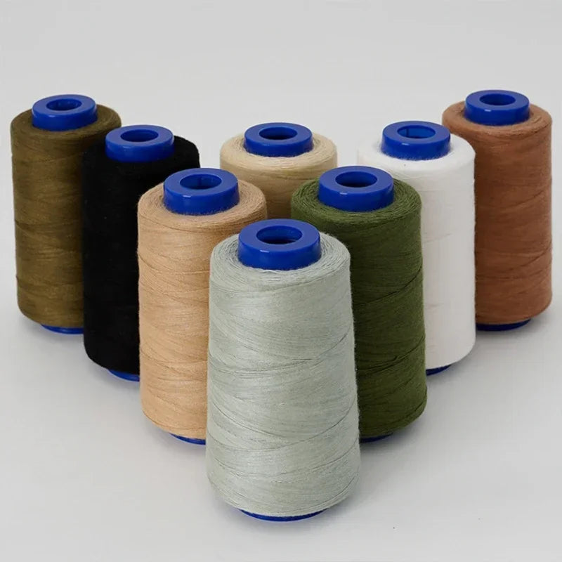 A collection of spools of heavy-duty polyester thread in various colors including brown, black, beige, green, and white.
