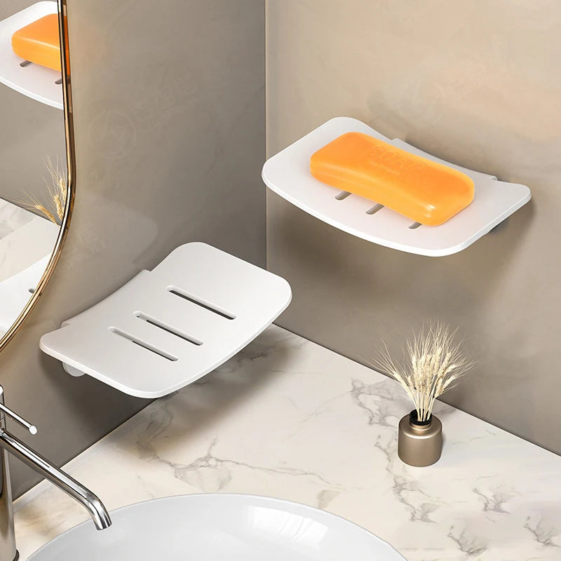 A white wall-mounted soap dish with an orange bar is displayed on a marble countertop.