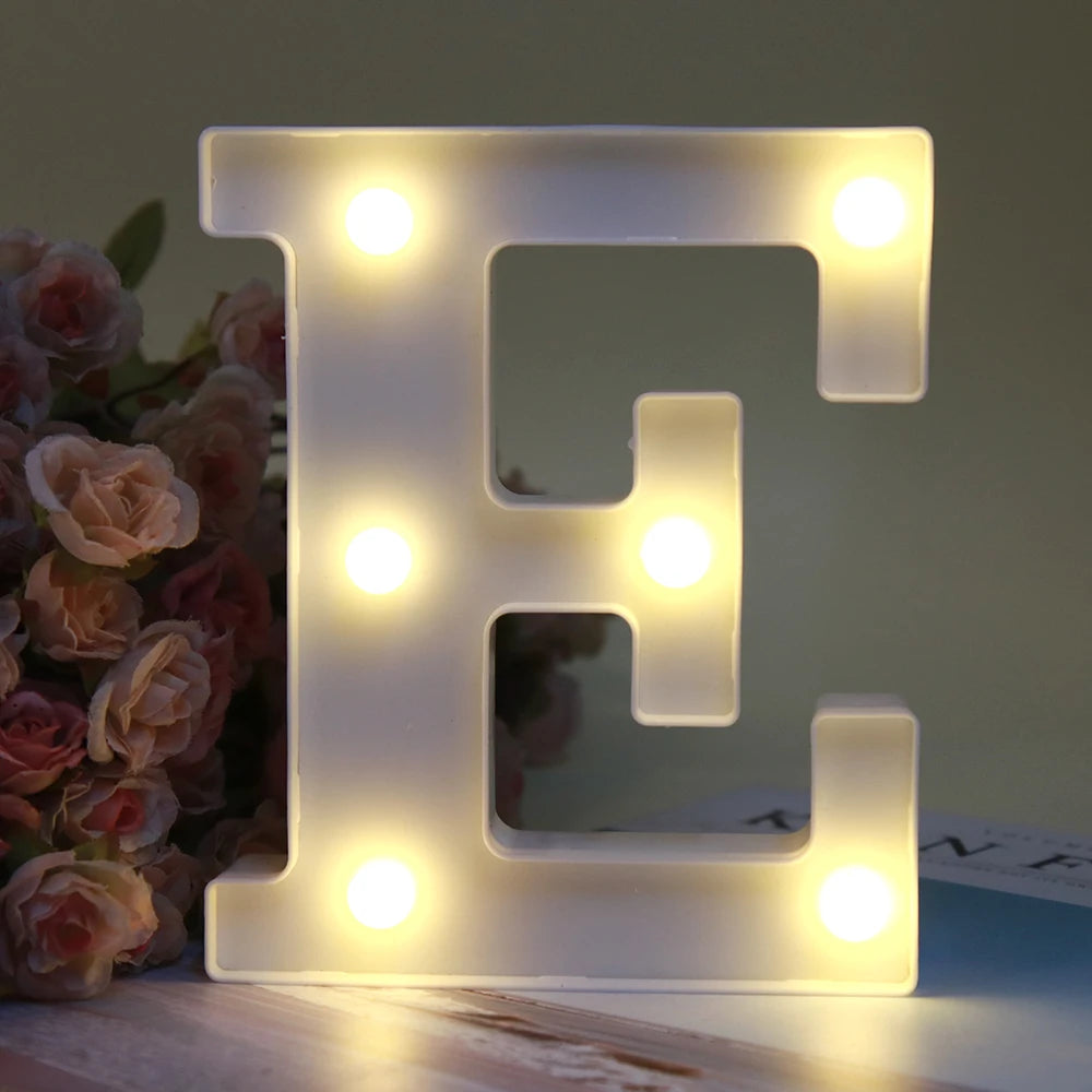 Lumière de nuit alphabétique LED brillante en forme de lettre E sur une surface en bois.