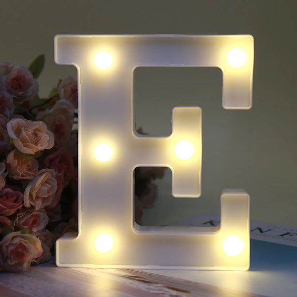 A glowing LED alphabet letter night light shaped like the letter E on a wooden surface.