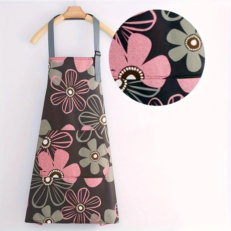 A floral print kitchen apron featuring pink, gray, and black flowers with an adjustable neck strap.