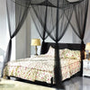 A bedroom featuring a dark wooden bed draped with sheer black mosquito netting.