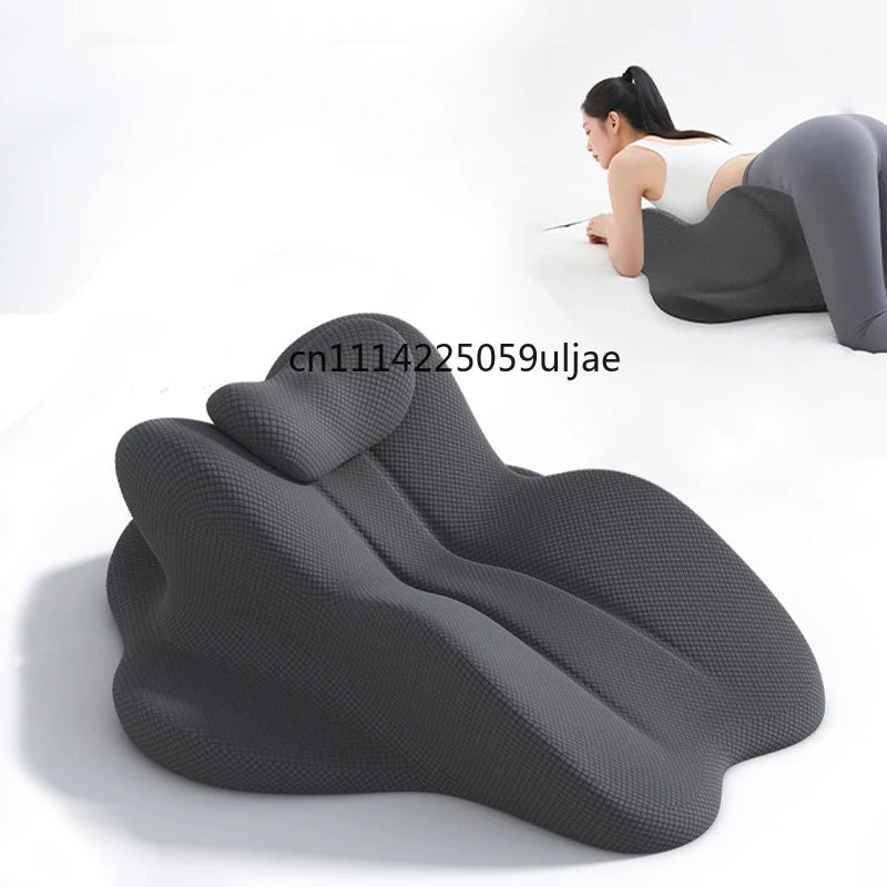 A dark gray ergonomic memory foam reading pillow is shown being used by a woman in a relaxed posture.