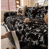 Schwarzes besticktes Chenille-Sofa-Handtuch mit weißen Blumenmustern auf einem Bett.