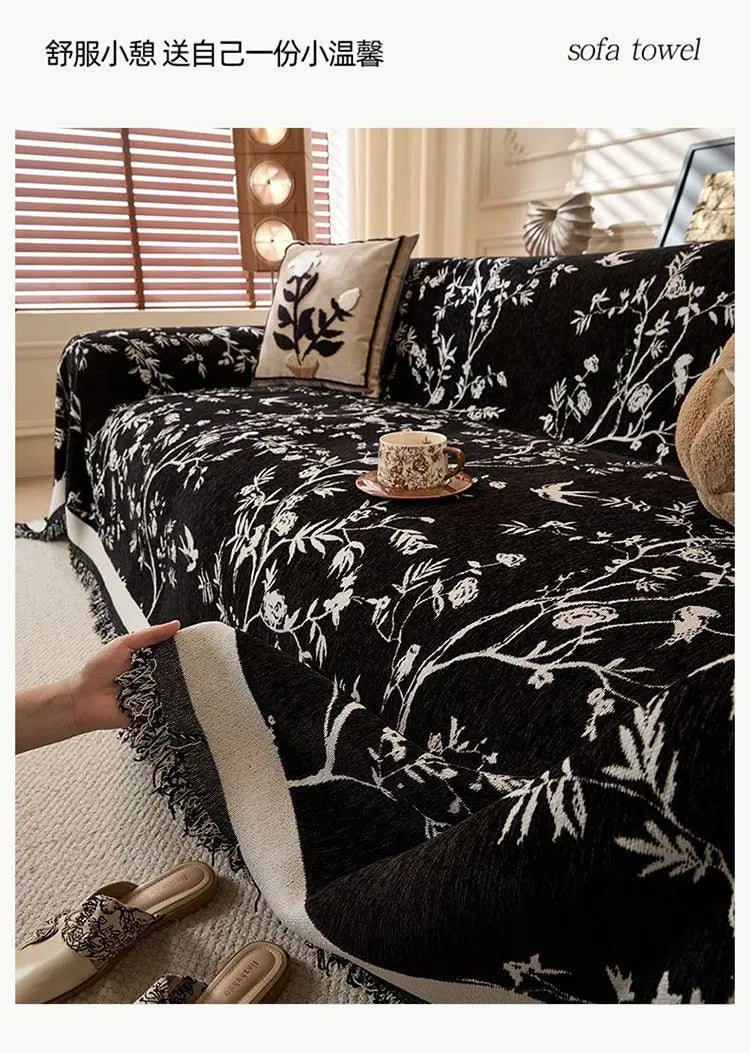 Schwarzes besticktes Chenille-Sofa-Handtuch mit weißen Blumenmustern auf einem Bett.