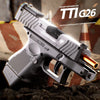 A silver pistol, the TTI G26, is shown in a close-up view resting on a dark surface.