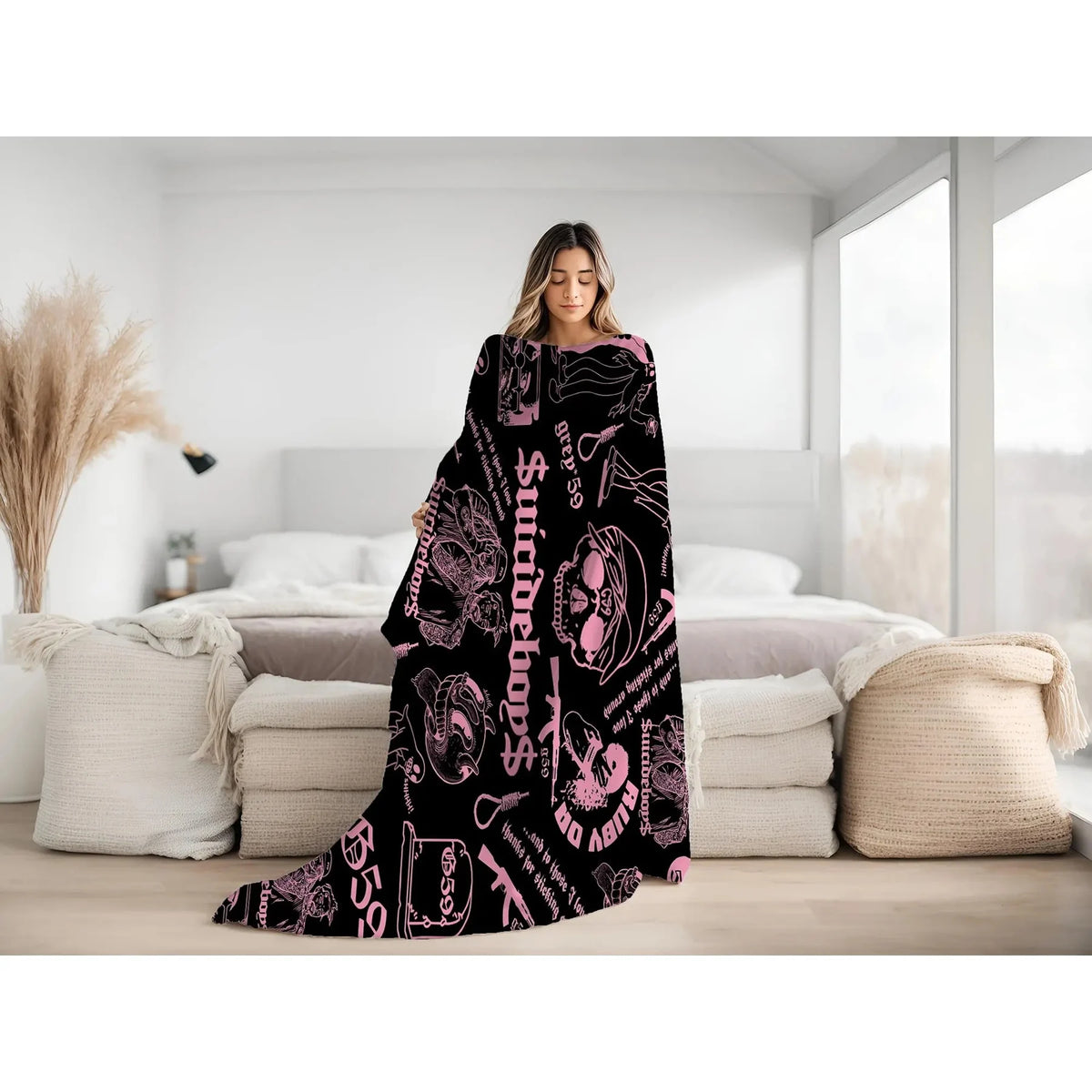 A woman models a black throw blanket featuring retro skull and clown horror art in shades of pink and black.