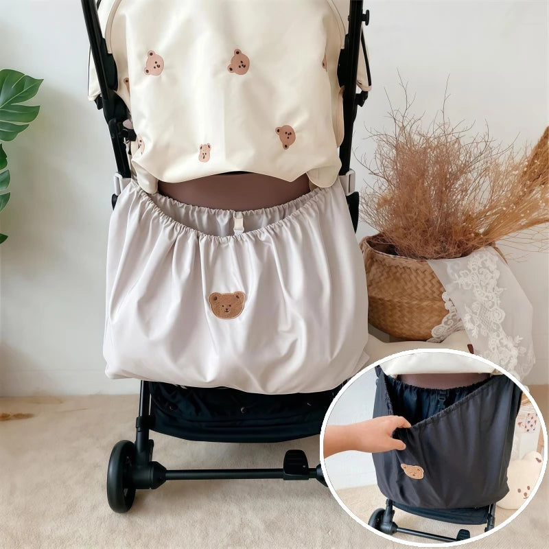 A beige bear-themed stroller organizer bag is shown attached to a stroller frame.