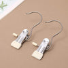 A pair of stainless steel clothespins with hooks used as a space-saving closet organizer.