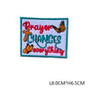 An embroidered letter patch featuring the text Prayer Changes Everything with a cross and butterfly design.