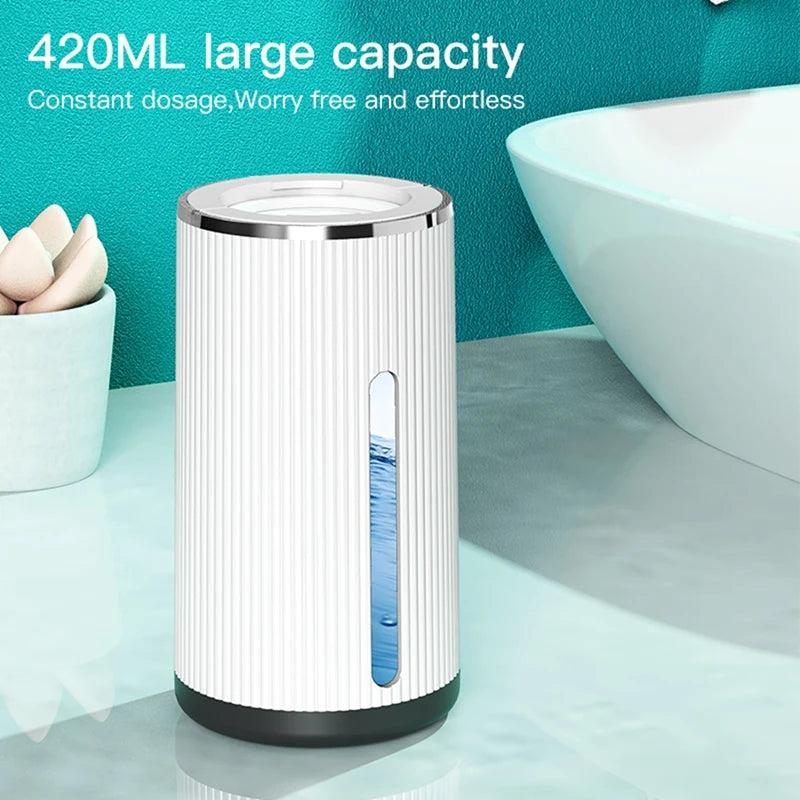 A white automatic foaming soap dispenser with a blue liquid, sitting on a light surface.