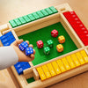 A wooden box game featuring colored dice arranged in slots, with a hand holding blue dice.