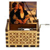 A vintage hand-crank wooden music box with a decorative wooden box and a brass crank handle.