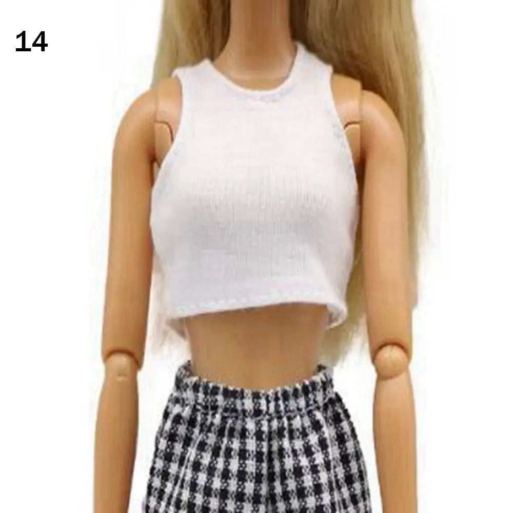 A fashion doll wearing a white cropped tank top and a black and white plaid skirt.