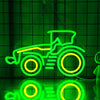 A neon sign shaped like a tractor, glowing green and yellow, is displayed against a dark green grid background.