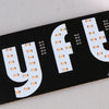 A black sign featuring the letters YFT in white LED lights, designed for ride-share vehicles.