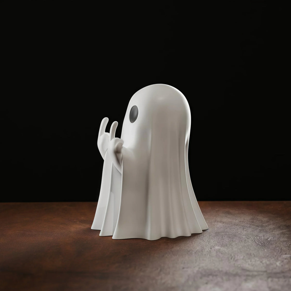 A white resin statue of a ghost with arms outstretched and a middle finger, displayed on a dark wooden surface.
